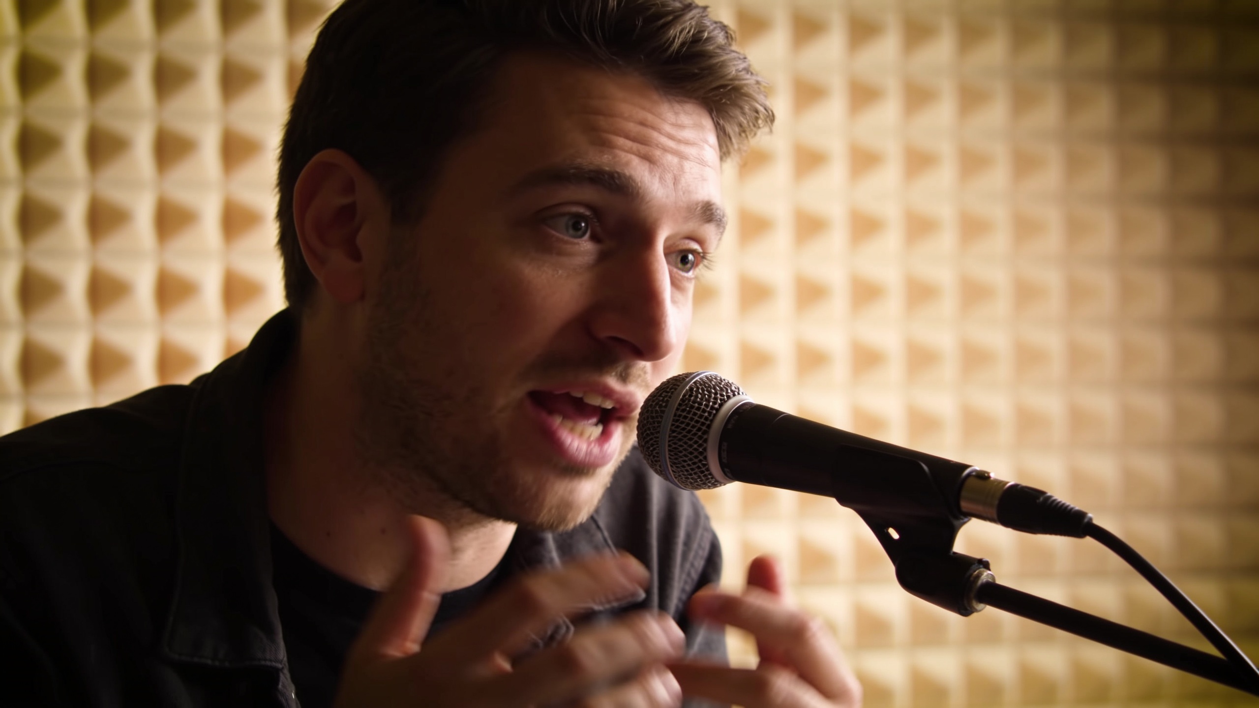 Person speaking into a microphone in a studio booth