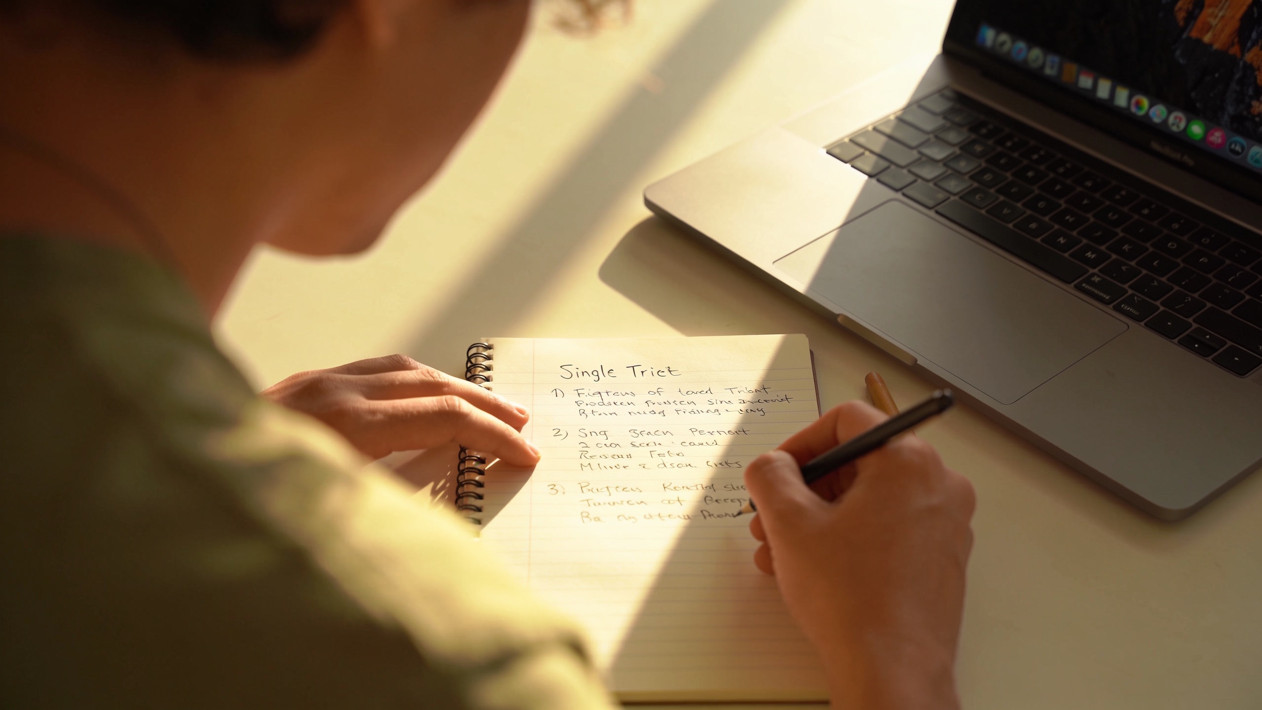 Creator writing a jingle brief next to a laptop